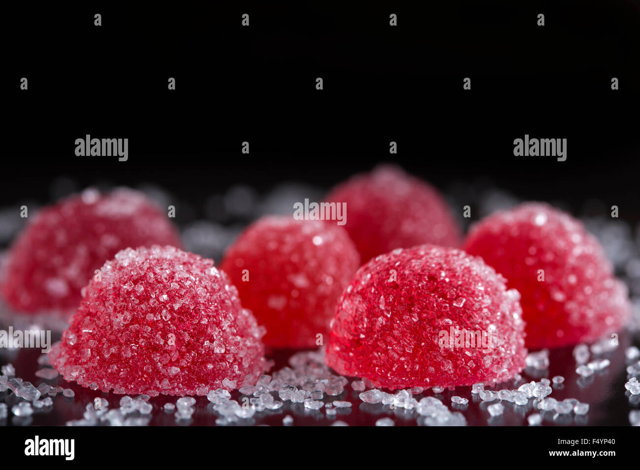 Red jelly caramelle con zucchero bianco su sfondo nero Foto Stock