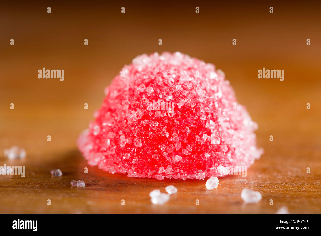 Uno rosso jelly caramelle con zucchero bianco su sfondo di legno Foto Stock