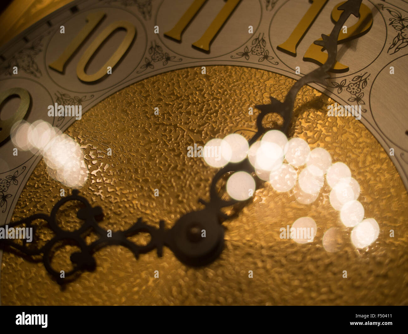 Le mani di un vecchio orologio a pendolo con luci riflesse Foto Stock