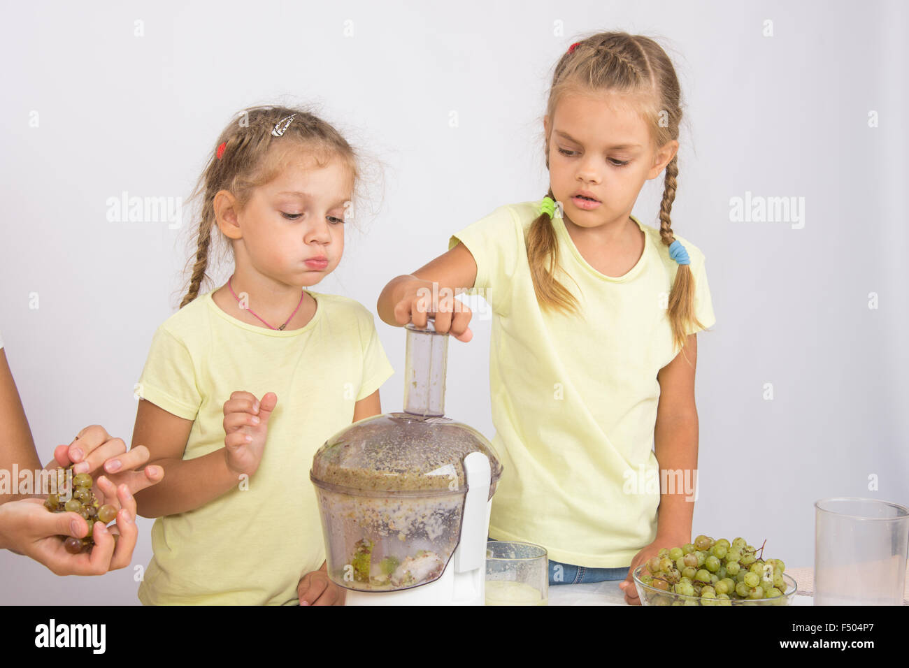 Due ragazze in una tavola succo spremuto da le pere e le uve con una centrifuga Foto Stock