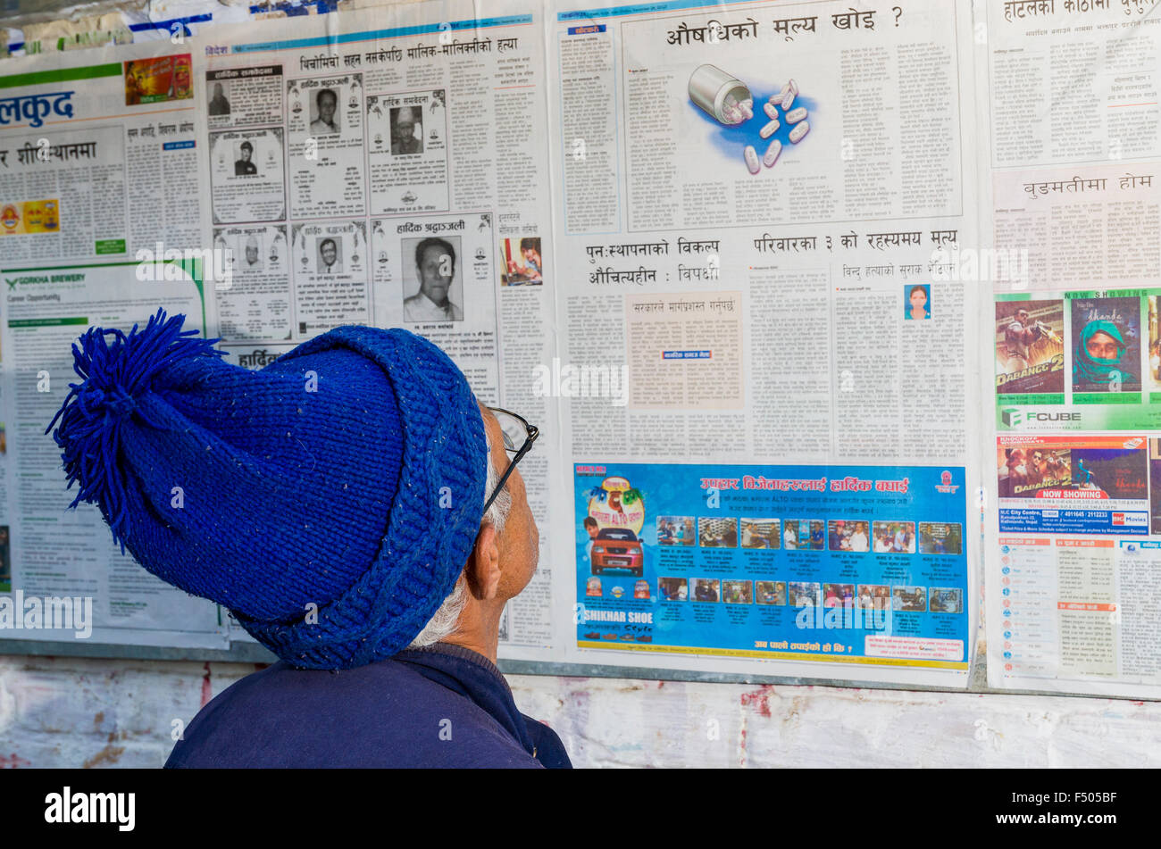 Uomo con blue hat leggendo un articolo su medicina in un giornale Foto Stock