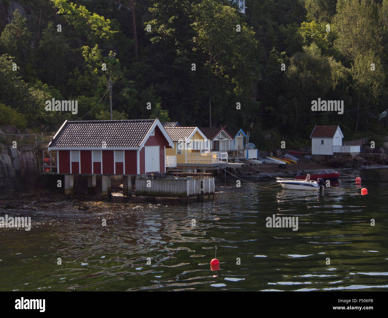 Vista da una crociera di un giorno sul fiordo di Oslo in Norvegia, bagno privato case e pontili sotto le scogliere ripide Foto Stock