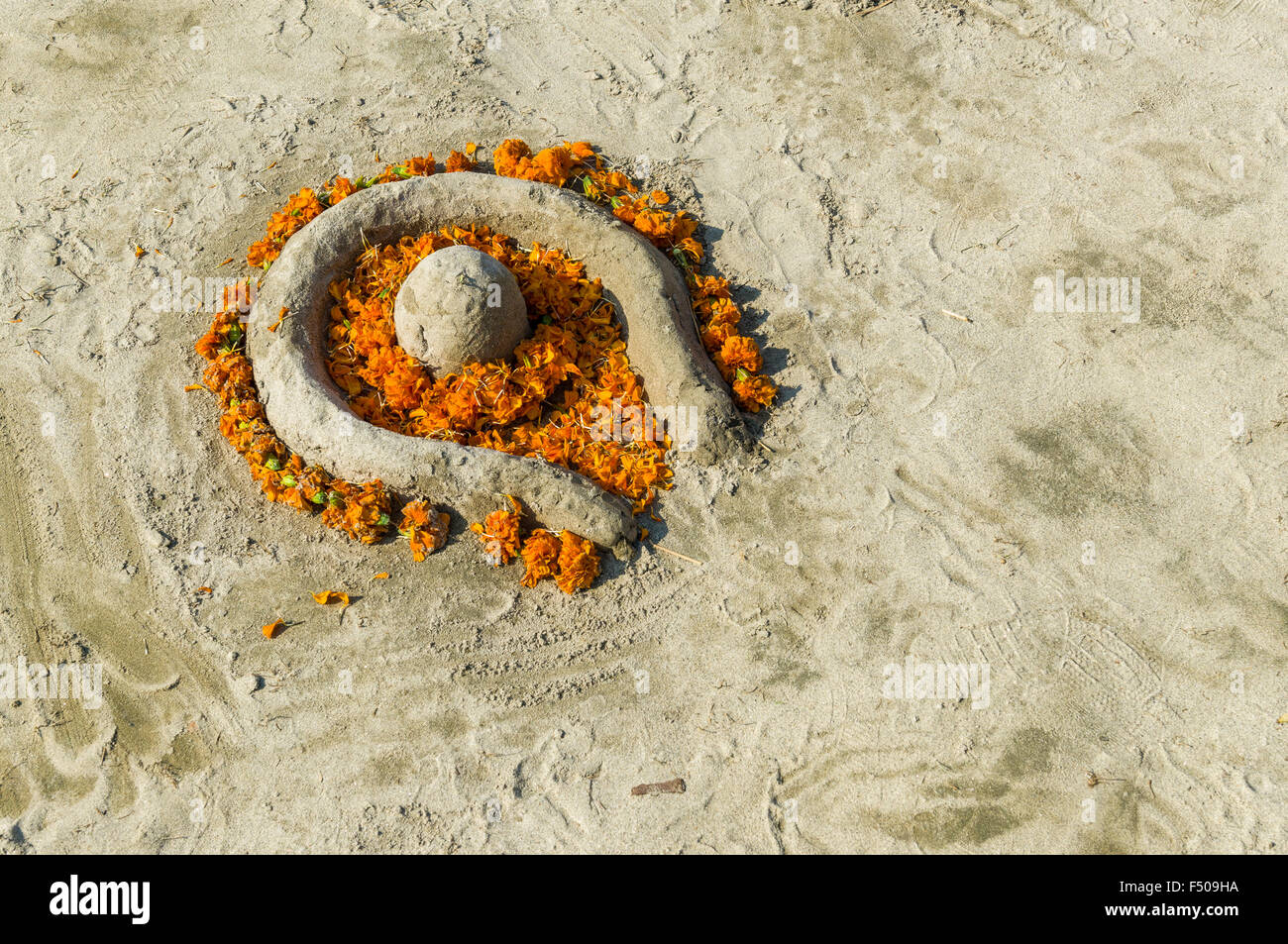 Shiva lingam di sabbia e fiori al sangam, alla confluenza dei fiumi Gange e yamuna e saraswati, al kumbha mela Foto Stock