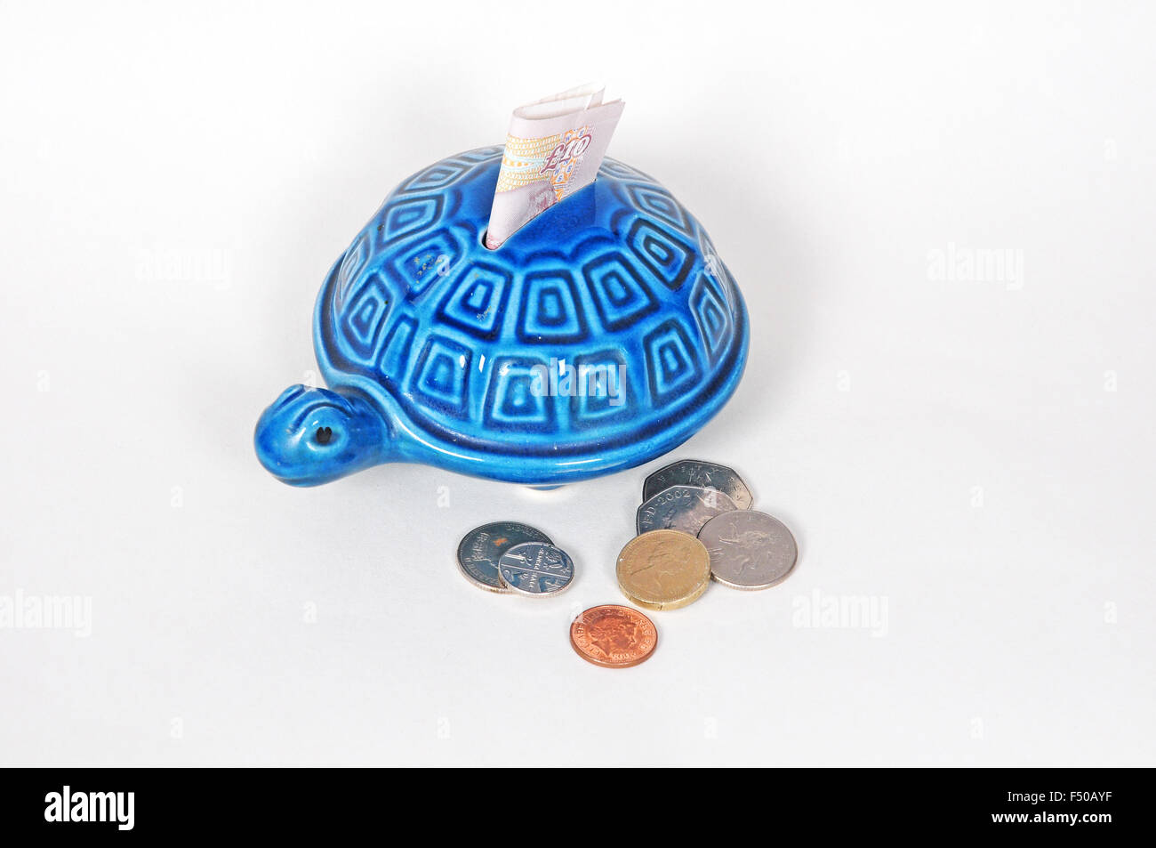 Tartaruga scatola di denaro con dieci pound nota e monete sterling Foto Stock