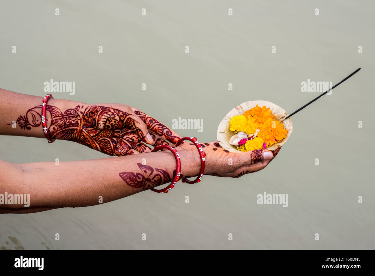 Una coppia di henna dipinto le mani sono in possesso di un Deepak, un fiore che offre, al ghats del Sacro Gange Foto Stock