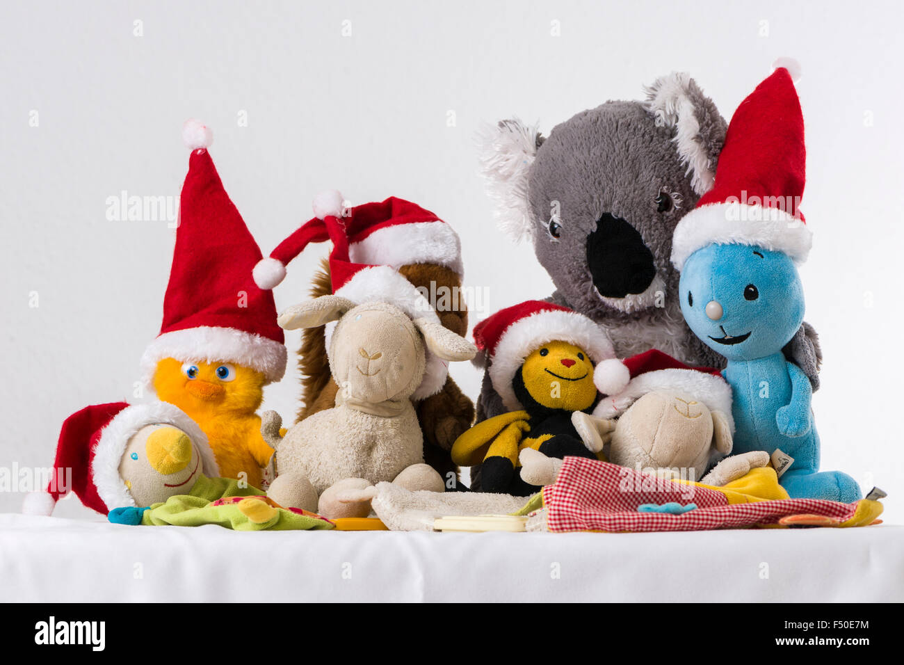 Molte colorate peluche, indossando il babbo natale cappelli, sono seduti insieme su un tavolo bianco Foto Stock