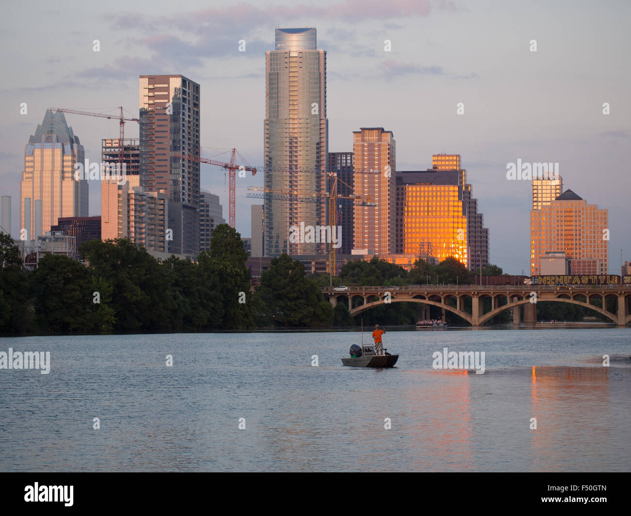 Un uomo la pesca al tramonto sul Lago Lady Bird di fronte alla Austin, Texas skyline Foto Stock