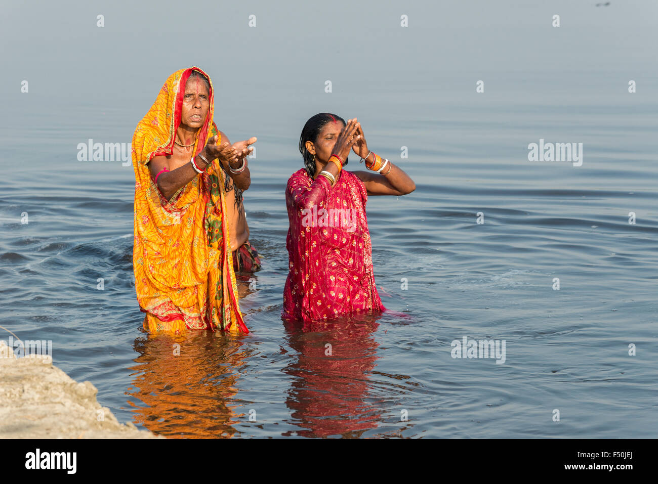 Due pellegrini femminile, le donne sono tenendo bagno e pregando nel sacro fiume Yamuna Foto Stock