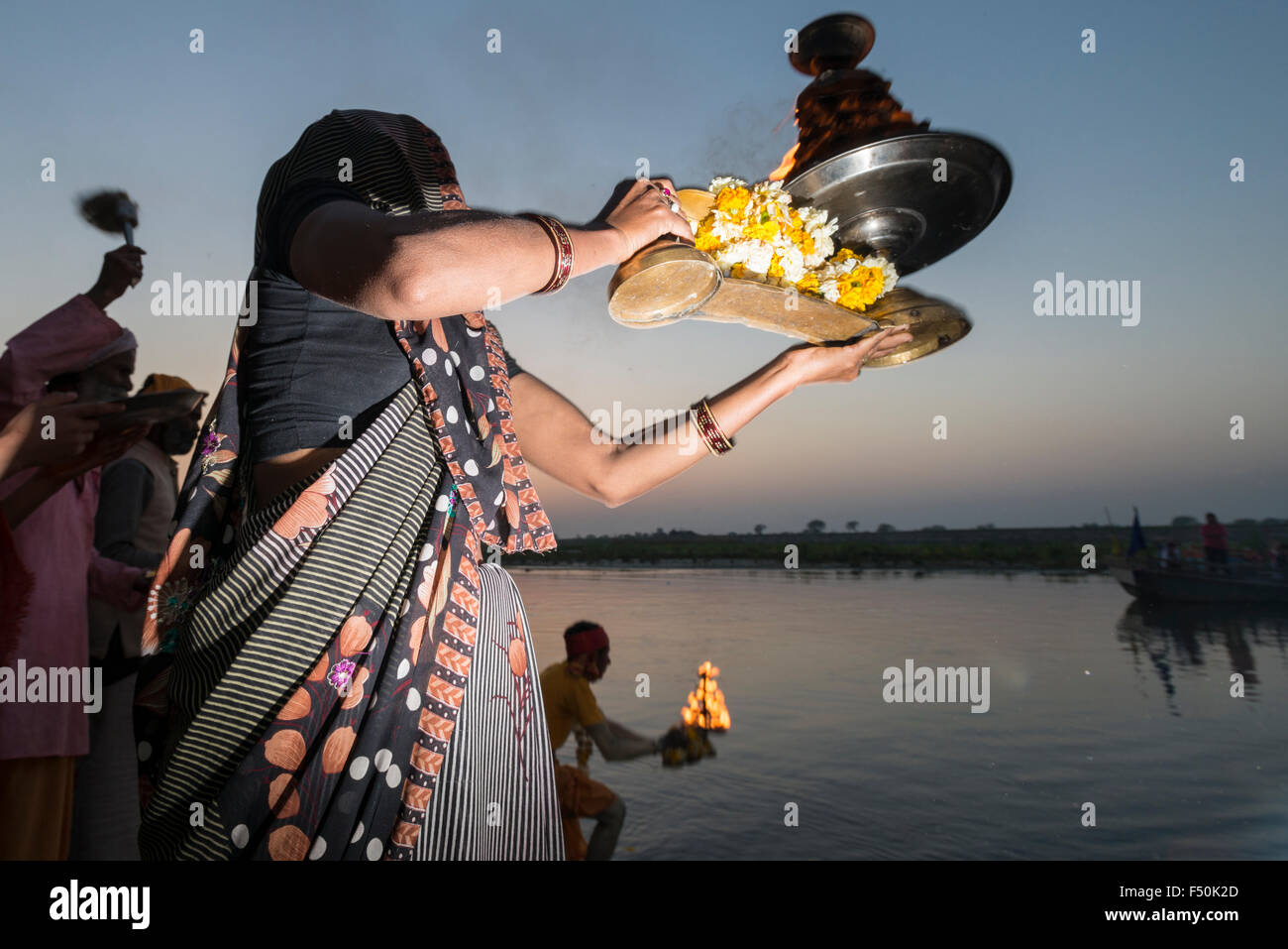 Una femmina del pellegrino, donna, celebra un rito, pooja, sul ghats presso il santo fiume Yamuna Foto Stock