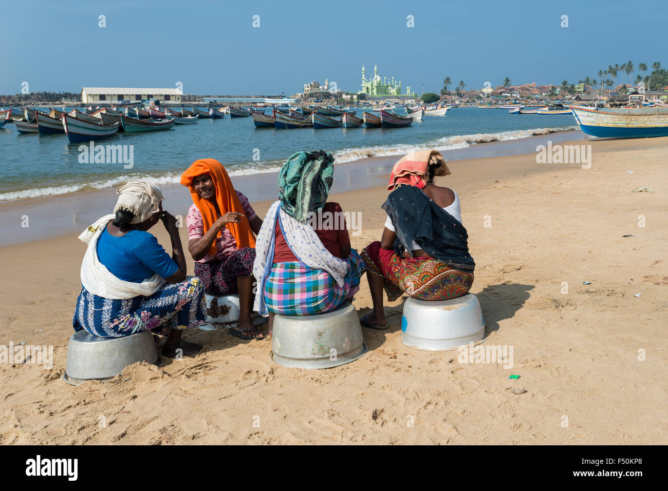 Quattro donne in appoggio sulla spiaggia del religeously suddiviso il villaggio dei pescatori dopo il quotidiano mercato del pesce, la moschea mohijedin s Foto Stock