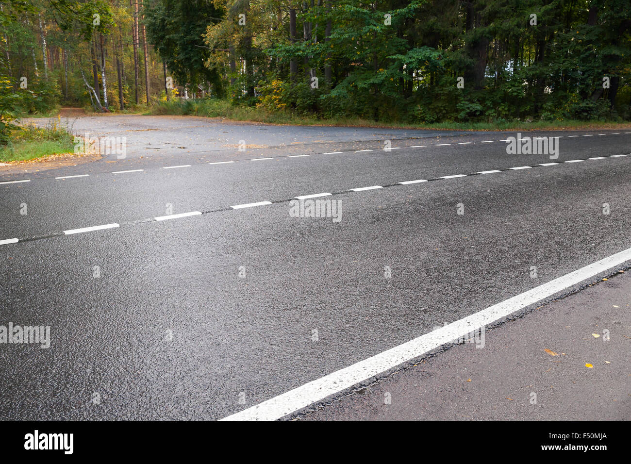 Wet rural strada asfaltata a strisce con linea di demarcazione Foto Stock