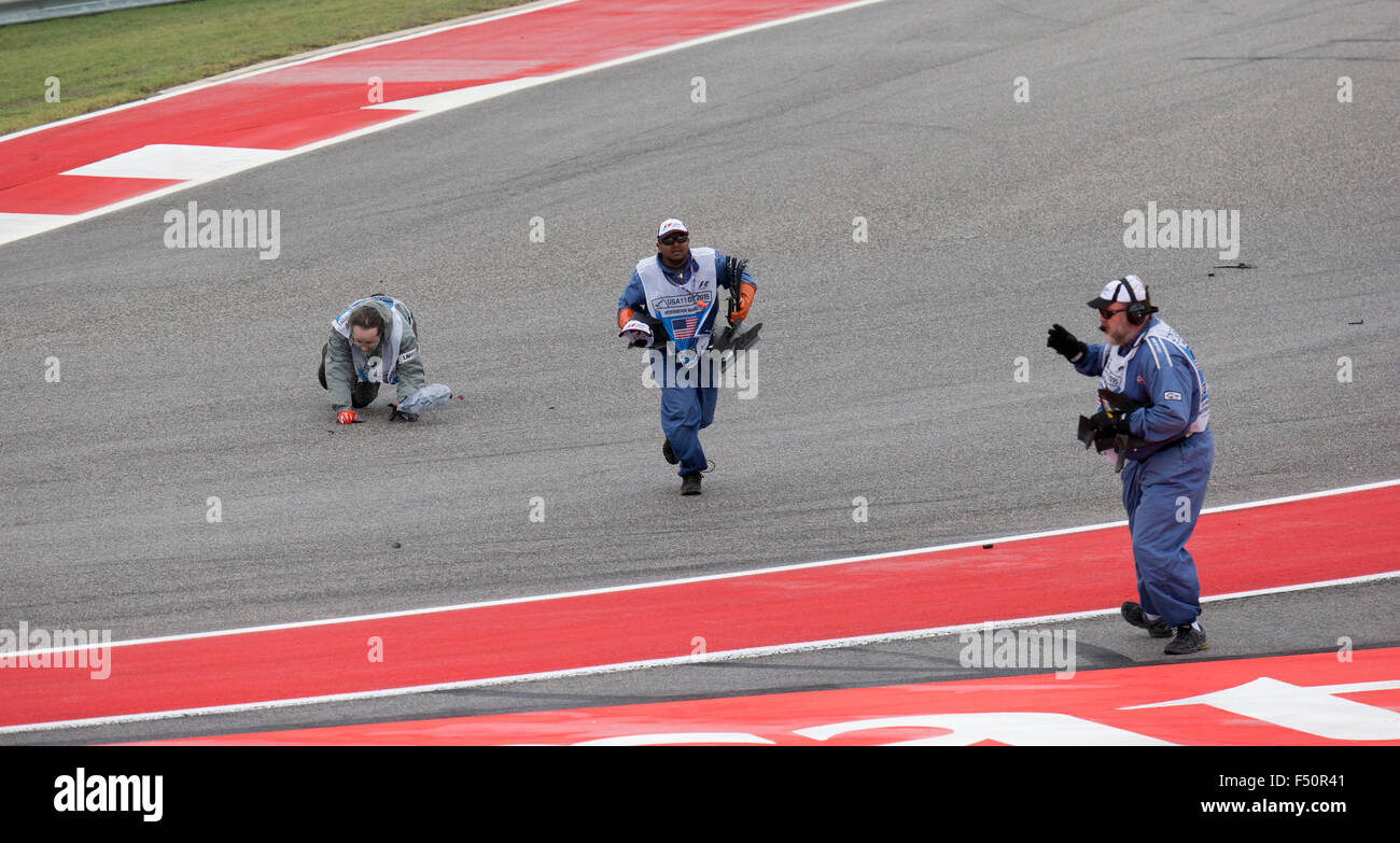 Austin, Texas USA Ottobre 25, 2015: Via funzionari pick up disseminato di pezzi di Nico Rosberg di gara auto in giro uno come lui entra in collisione con il compagno di squadra Lewis Hamilton al primo giro del Gran Premio degli Stati Uniti di Austin. Hamilton ha vinto la pioggia-imbevuta di gara. Foto Stock