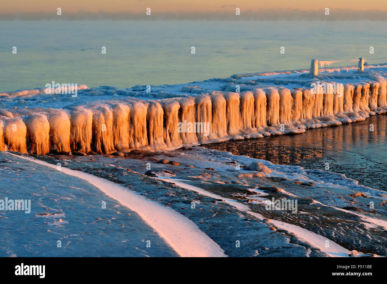 Il ghiaccio si forma su una struttura di frangionde in Chicago's 31st Street Harbour mentre riflette l'inizio della luce del sole che sorge sulla scena. Chicago, Illinois, Stati Uniti d'America Foto Stock
