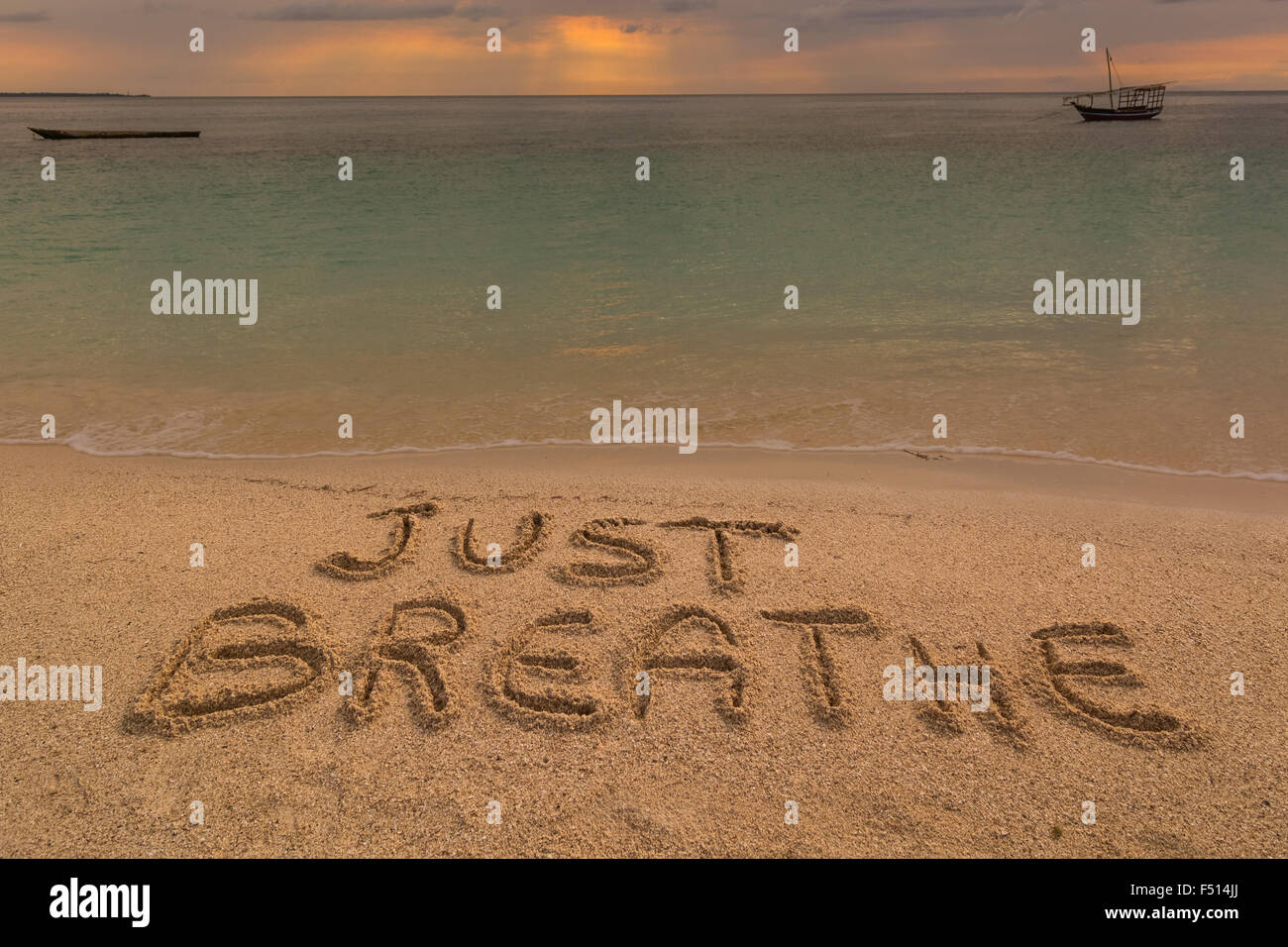 Nella foto una spiaggia al tramonto con le parole sulla sabbia 'appena respirare". Foto Stock