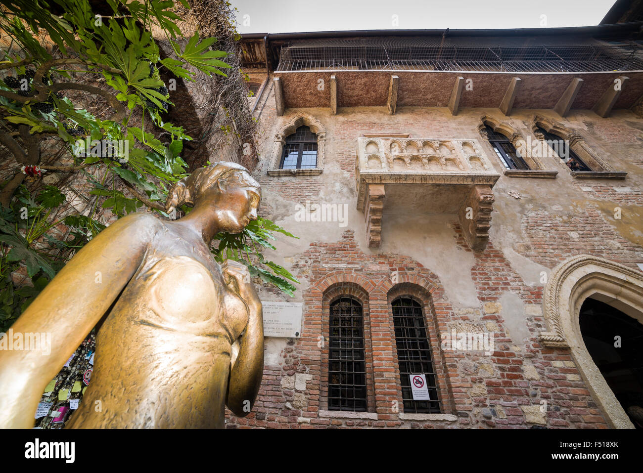 La statua di ottone di Giulietta nel cortile della casa juliets con il famoso balcone Foto Stock