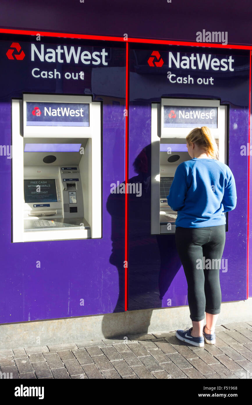 Una giovane donna di ritirare denaro contante in un Natwest Bank ATM o Bancomat Foto Stock