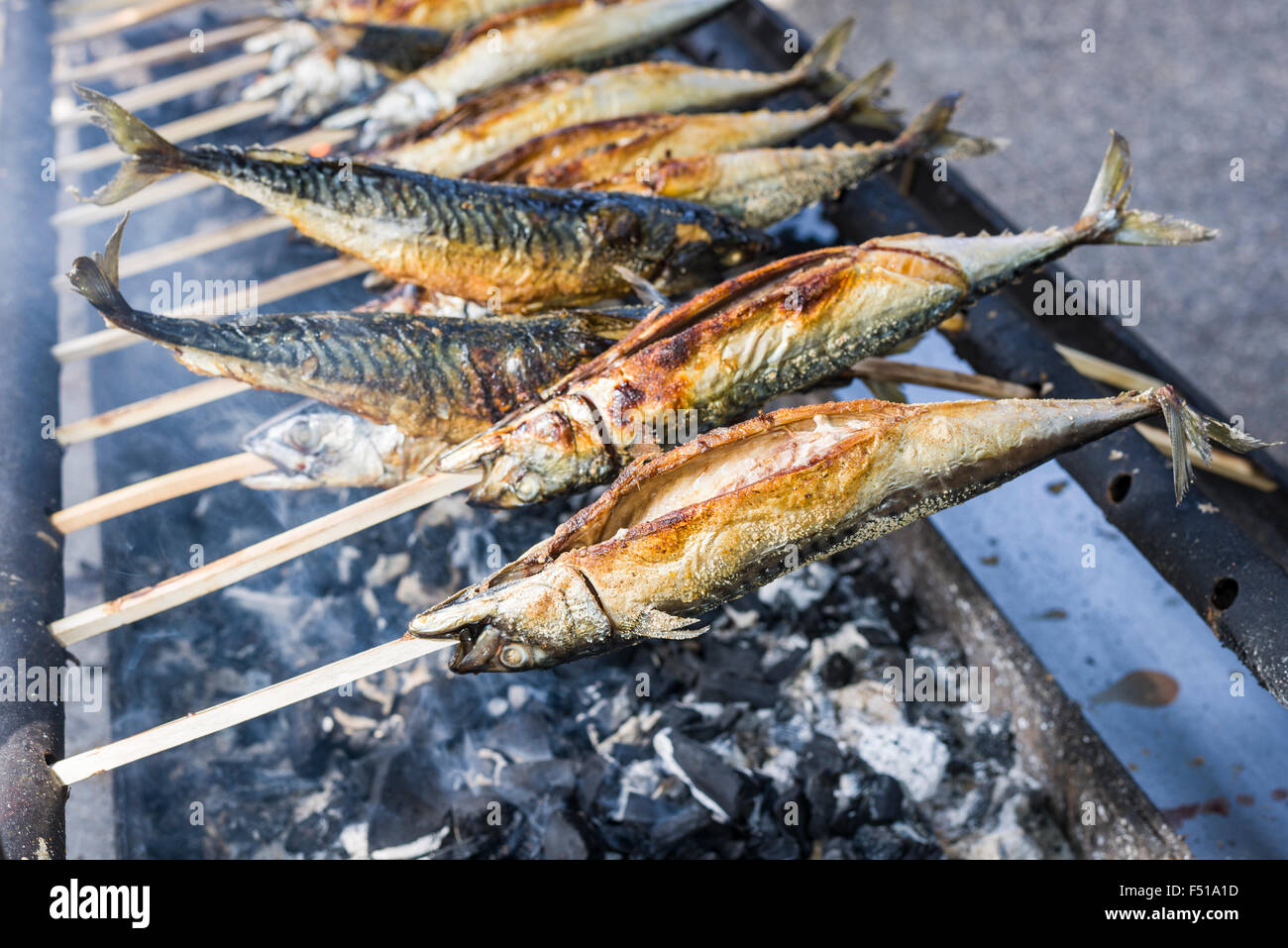 Stockfisch, un piatto di pesce preparati su un bastone di legno, è alla griglia su un barbecue Foto Stock