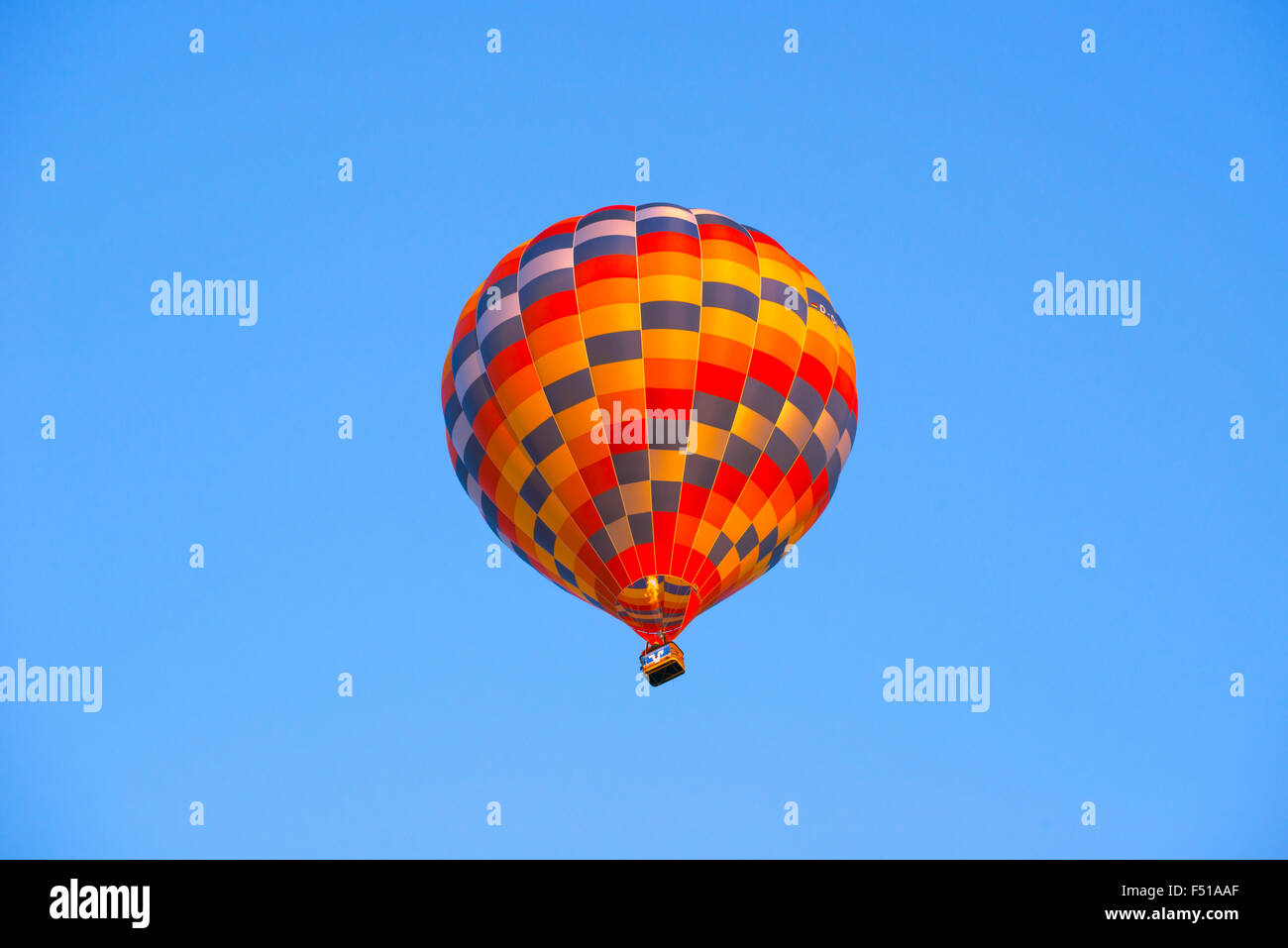 Una colorata mongolfiera è ascendente nel cielo blu Foto Stock