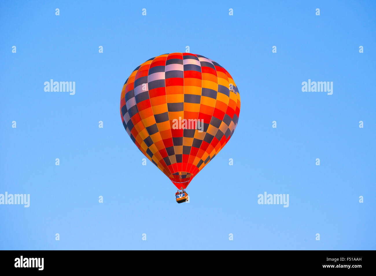 Una colorata mongolfiera è ascendente nel cielo blu Foto Stock