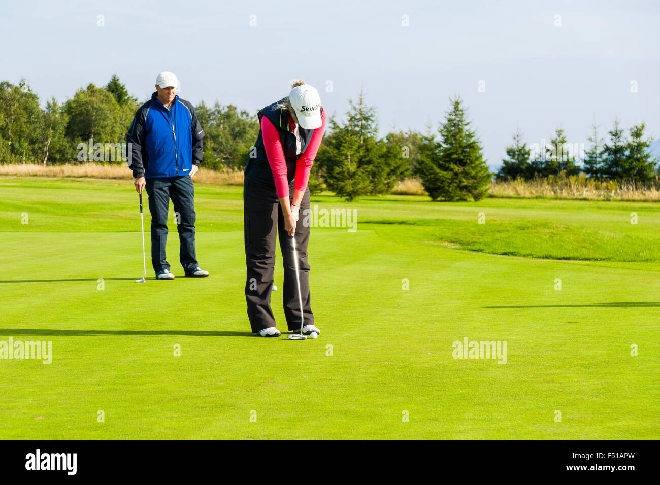 Un uomo e una donna sta giocando a golf su un verde prato Foto Stock