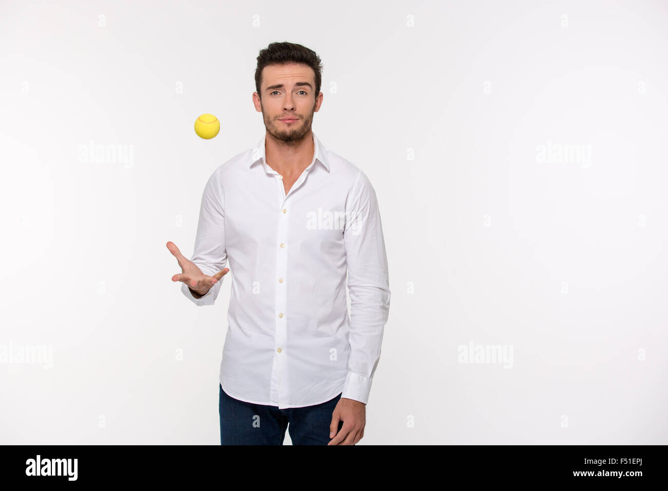 Ritratto di un uomo bello gettando palla da tennis isolato su uno sfondo bianco Foto Stock