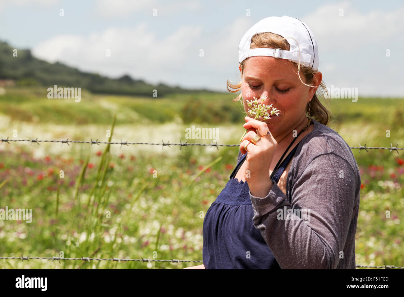 Giovane donna bionda teen odori fluisce in un campo di fiori selvatici Foto Stock