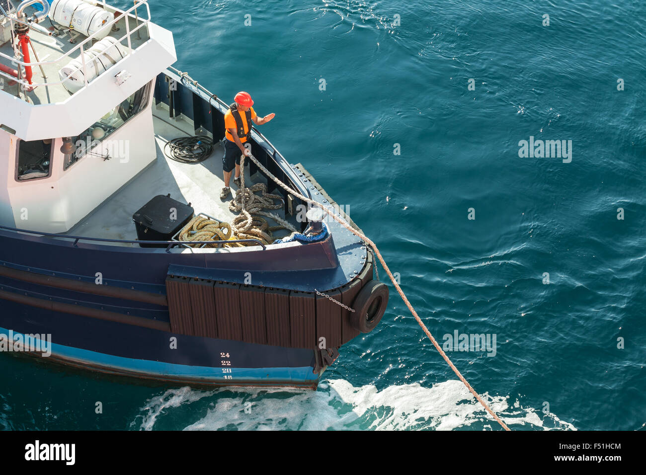 Ajaccio, Francia - 30 Giugno 2015: operazioni portuali, l'uomo al lavoro con funi su un arco di piccolo rimorchiatore Foto Stock