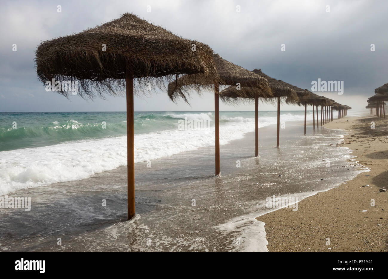 Spiaggia mediterranea con ombrelloni durante le giornate di cattivo tempo, Spagna. Foto Stock