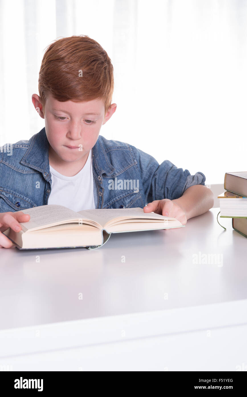 Ragazzo giovane legge molto concentrata in un libro Foto Stock