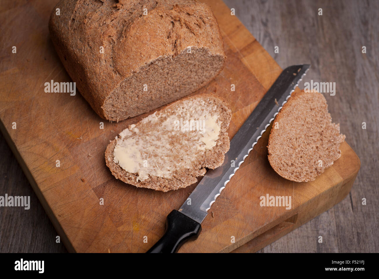Pane appena sfornato pagnotta di pane con una fetta imburrata Foto Stock