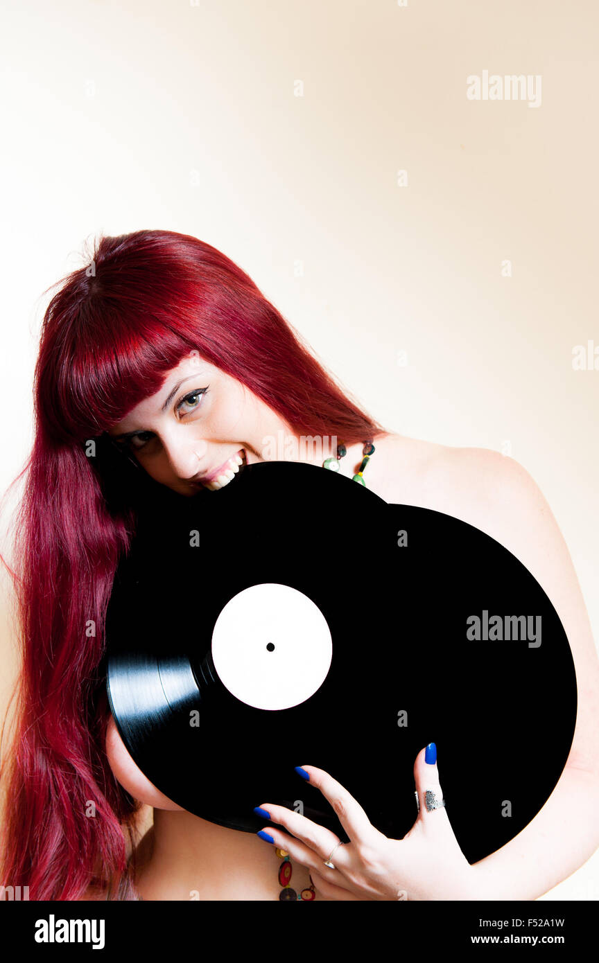 Giovane donna sorridente e mordere analog dischi in vinile Foto Stock
