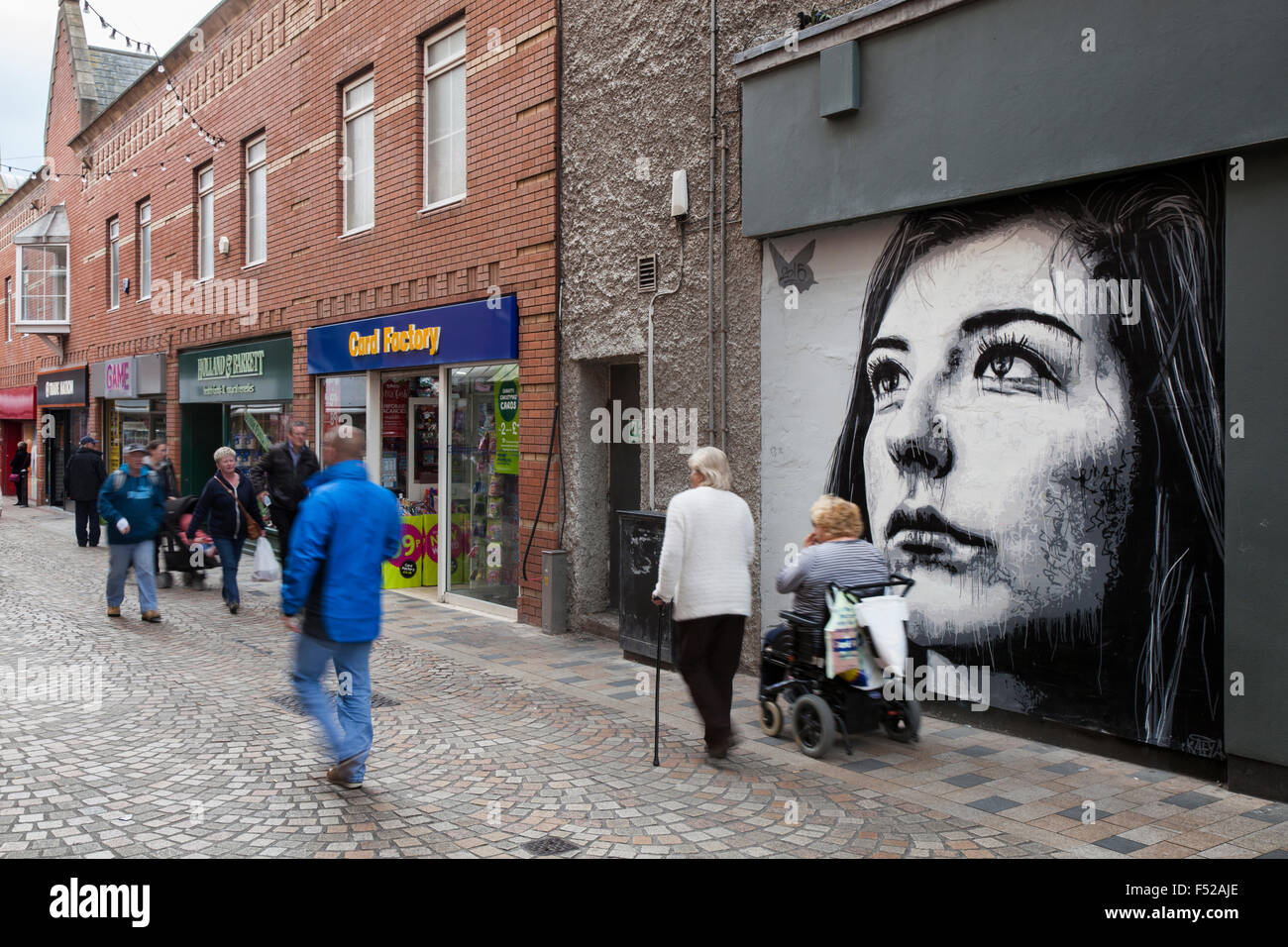Persone che passano in bianco e nero ritratto; arte urbana o graffiti a Blackpool, Lancashire, Regno Unito pedone passato walking street art graffiti dipinti a muro,. Foto Stock