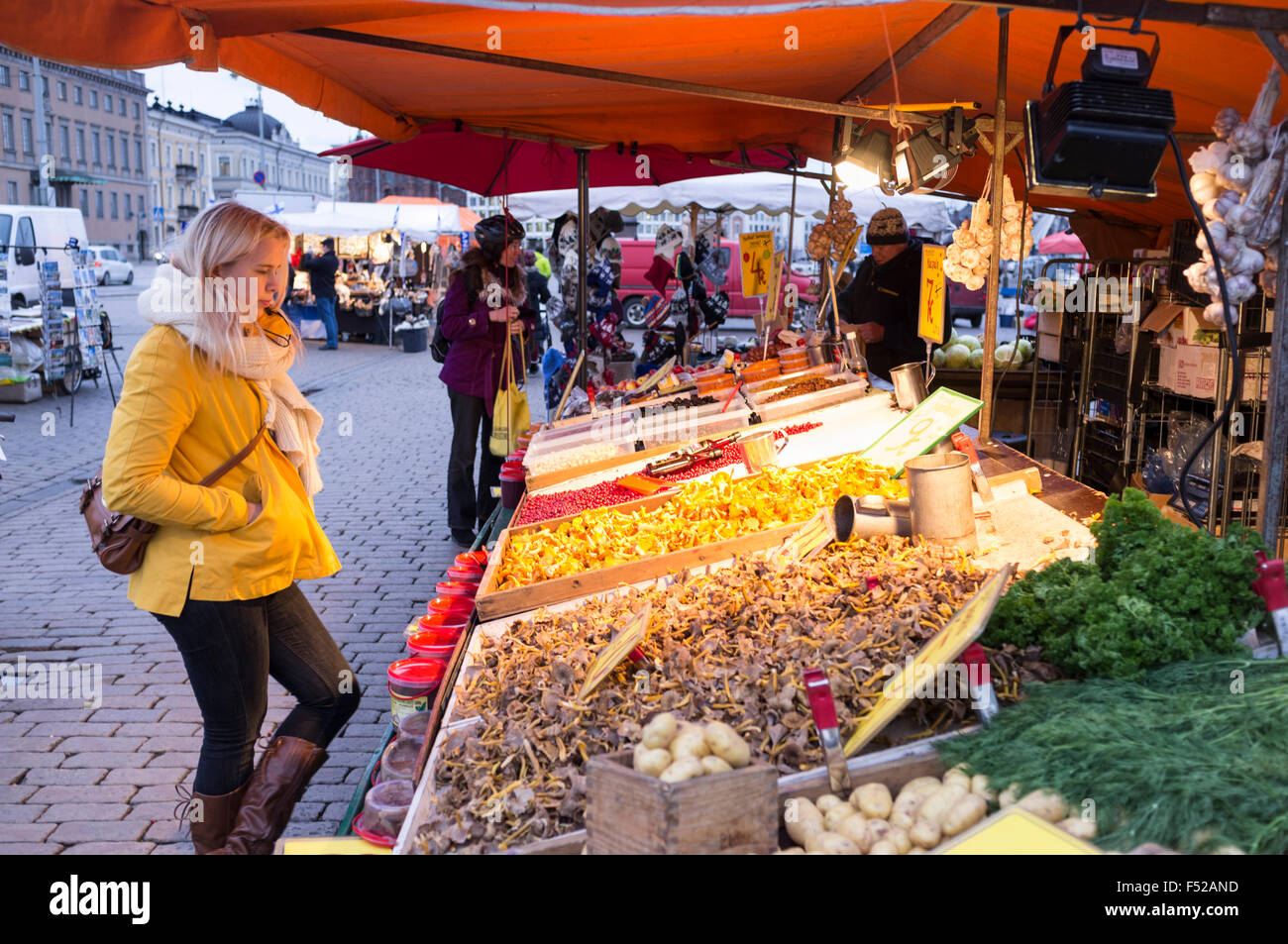 Giovane donna bionda fissando un cibo stallo nella piazza del mercato, Helsinki, Finlandia Foto Stock