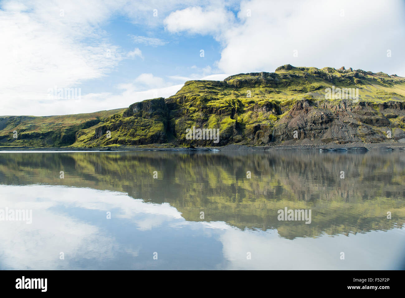 Cancella la riflessione di erba e rock hill in uno stato fuso lago glaciale in Islanda Foto Stock