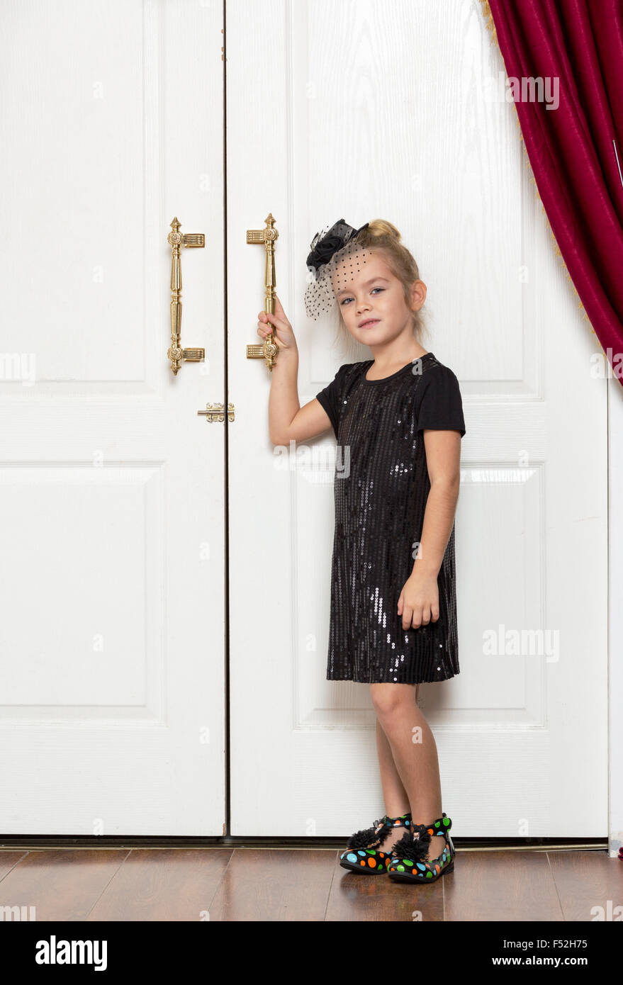 Bambina in abito da sera in piedi vicino alla grande porta Foto Stock