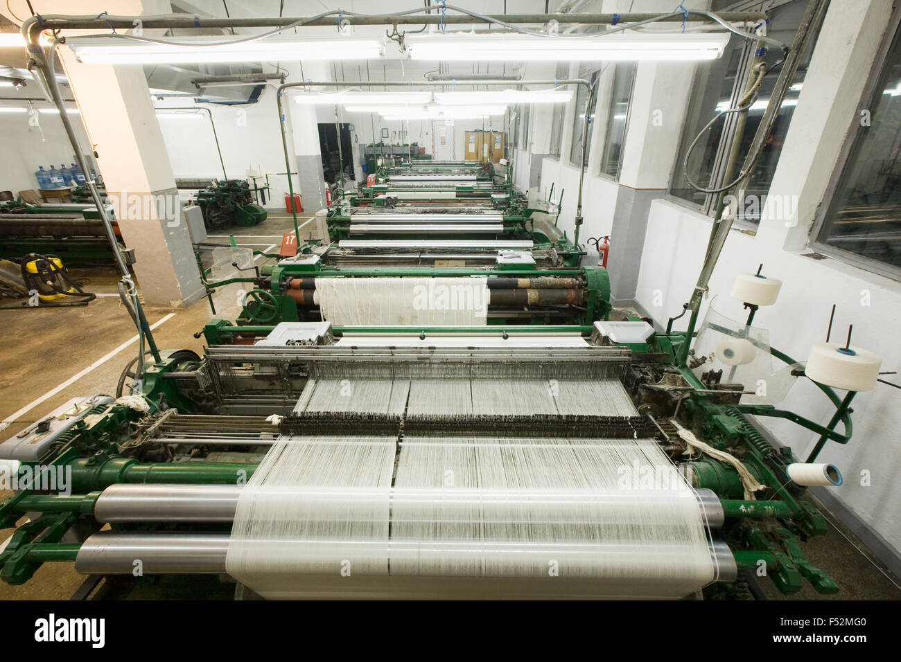 Macchine di tessitura schierate in fabbrica tessile Workshop Foto Stock