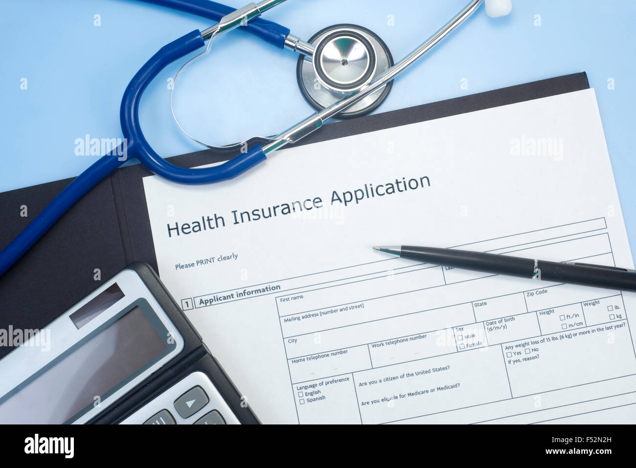 Domanda di assicurazione sanitaria con uno stetoscopio, calcolatrice e penna. Foto Stock