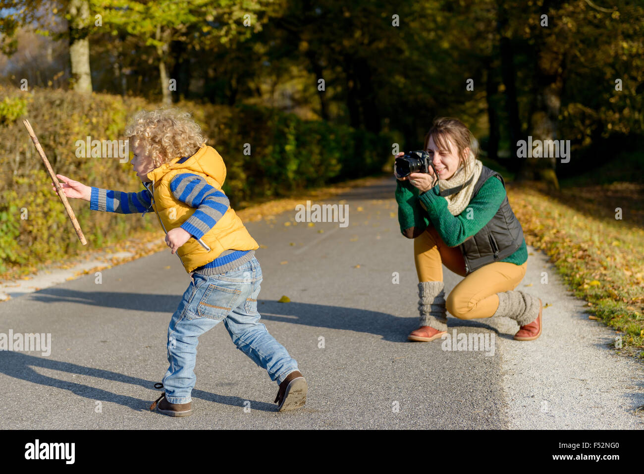 Allegro madre prendendo le foto di lei carino piccolo figlio nel parco, felice famiglia giovane avendo divertimento all'aperto, amore parentale e enj Foto Stock