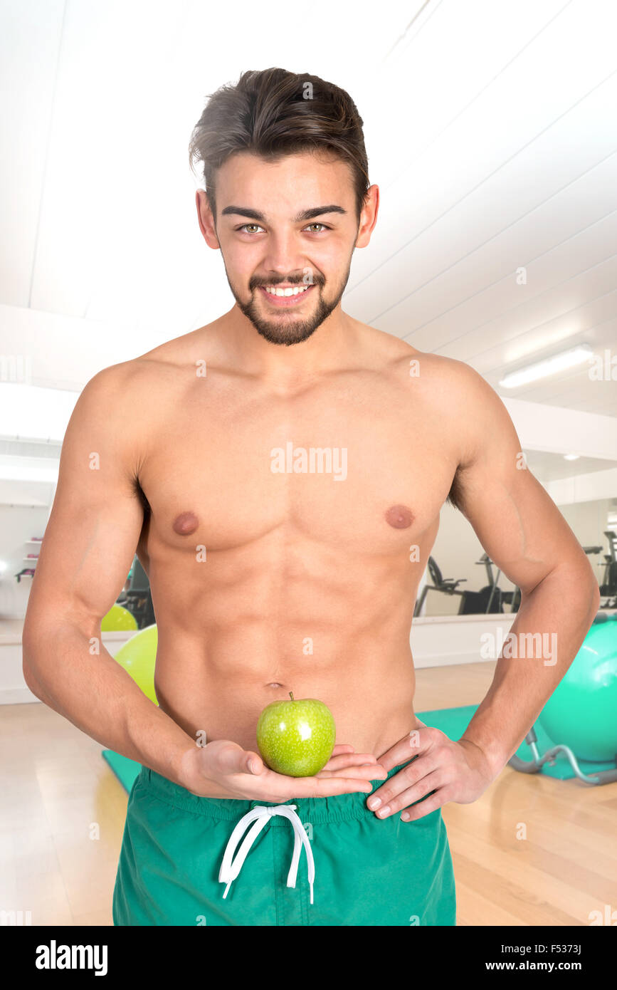 Bello e montare il giovane con un Apple in palestra Foto Stock