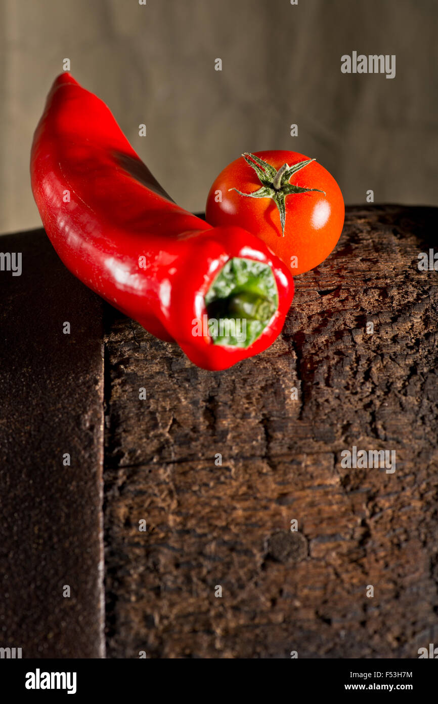 Pomodori e peperoni nel buio di sfondo di legno Foto Stock