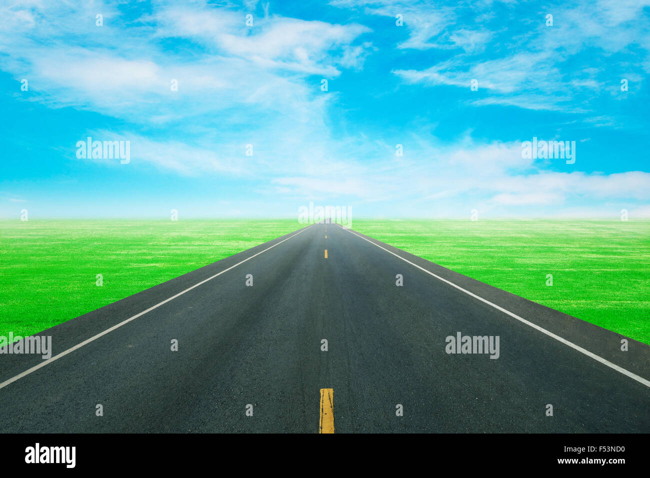 Strada asfaltata attraverso il campo verde con il blu del cielo Foto Stock