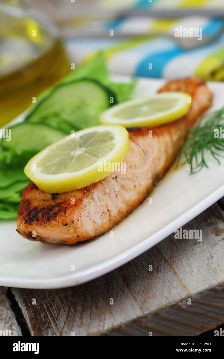 Salmone alla griglia con fettine di limone e verde insalata di lato Foto Stock