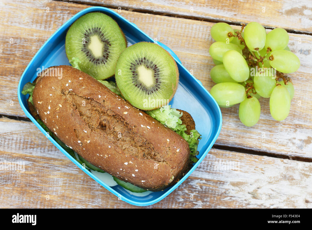 Scuola di sano pranzo scatola contenente pane di segale sandwich, kiwi e uva Foto Stock