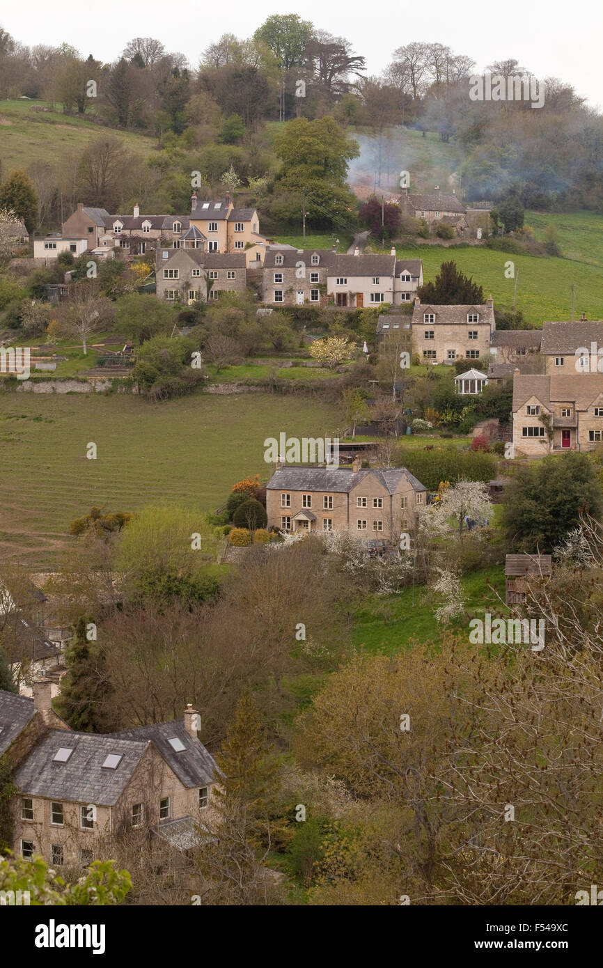 Una piccola comunità di case, particolare al Cotswold regione dell'Inghilterra, capovolta verso il basso di una collina in prima serata la luce. Foto Stock