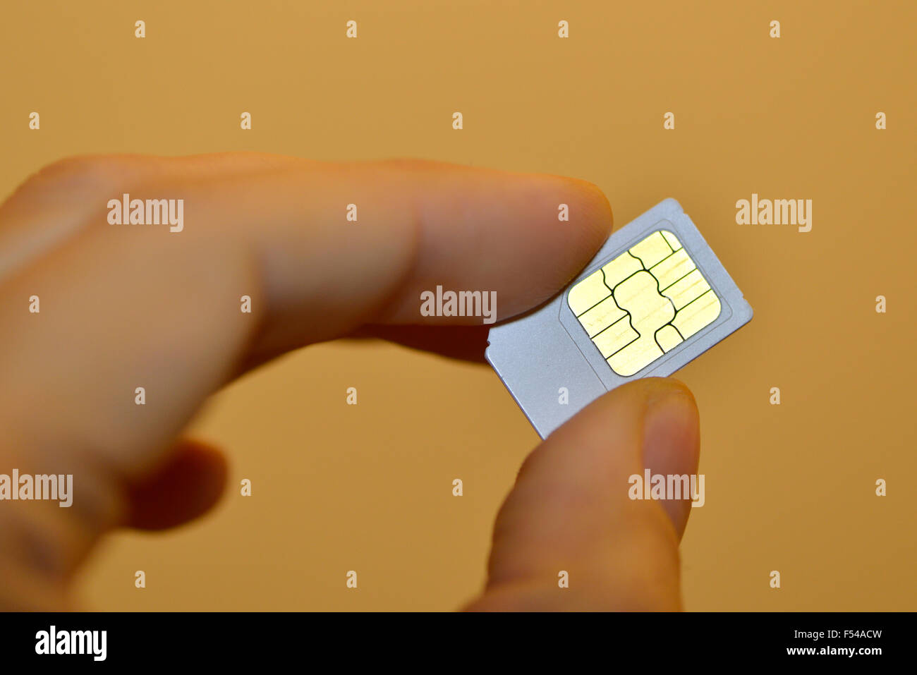 Mobile Phone SIM Card trattenuto tra le dita di un uomo Foto Stock