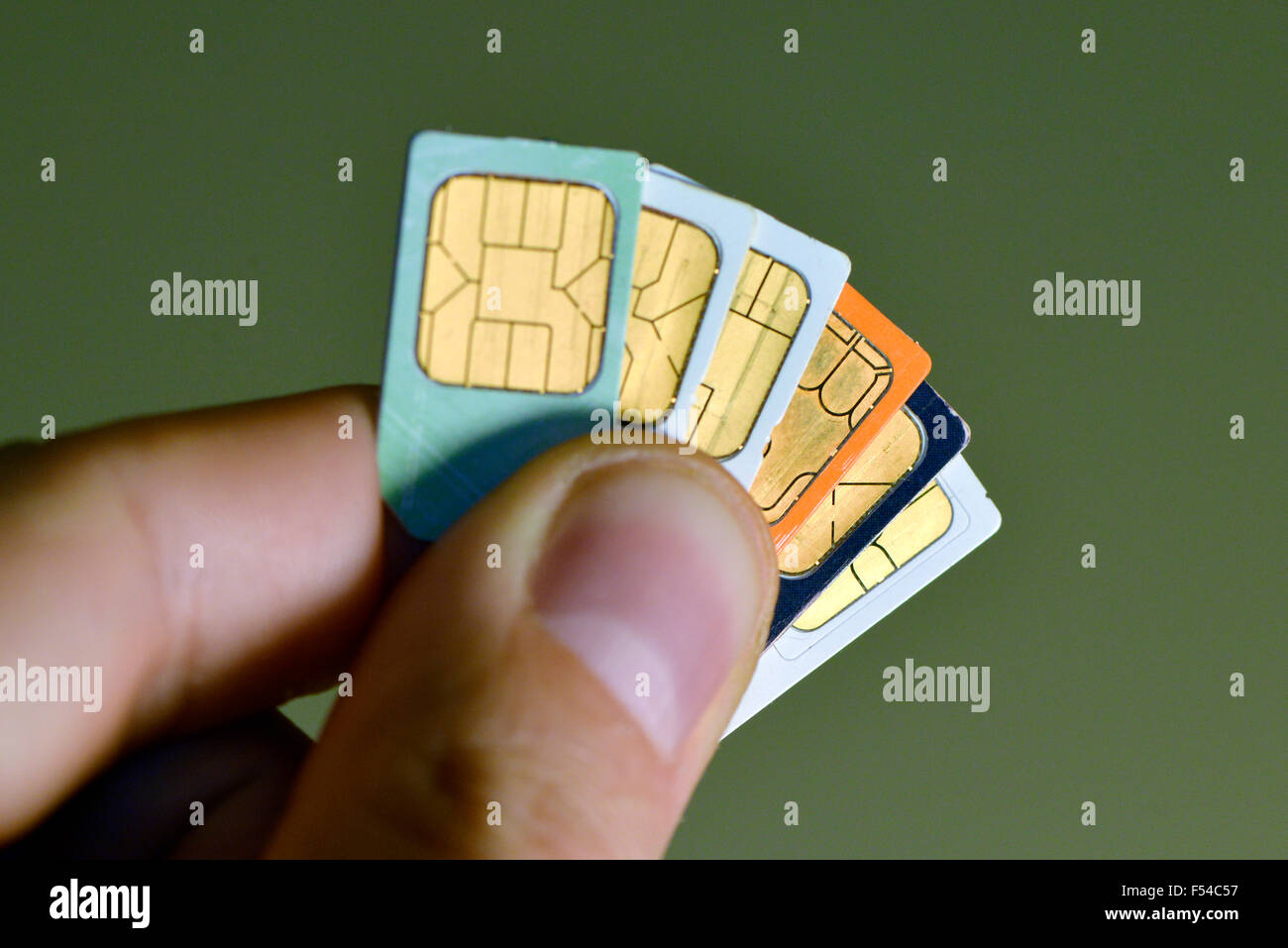 Telefono cellulare le schede SIM trattenuto tra le dita di un uomo Foto Stock