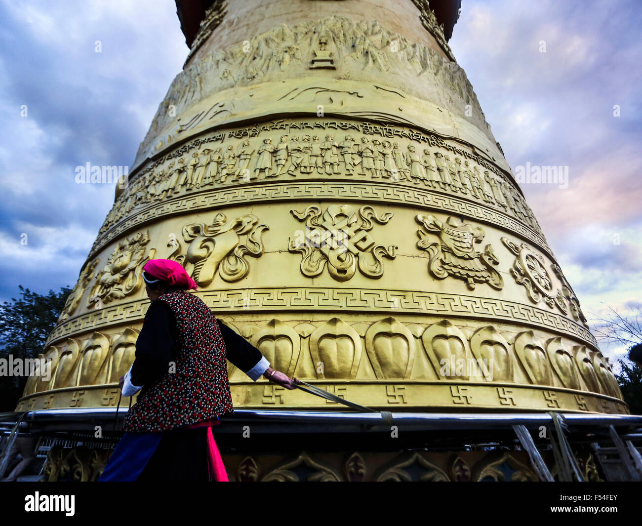Donna in tradizionali abiti tibetani girare una ruota di preghiera in Shangri-La in Cina Foto Stock