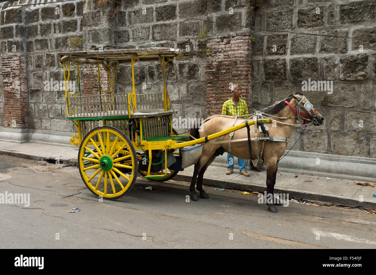 MANILA, Filippine - Giugno 7, 2015: Sconosciuto uomo con carro trainato da cavalli di Intramuros, la monumentale parte spagnola di Manila Foto Stock