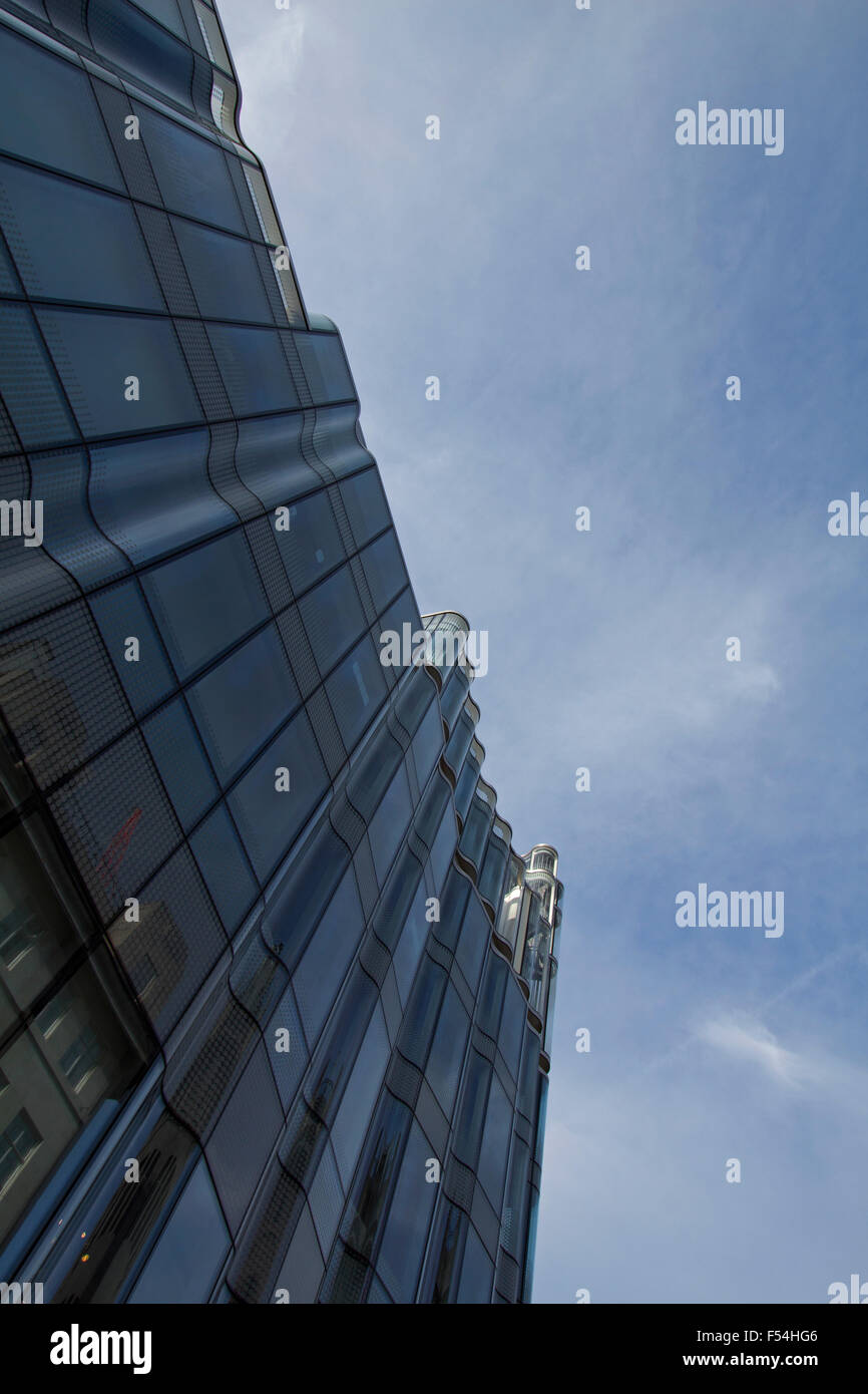Un edificio nel centro di Londra progettato con vetro curvo guardando verso l'alto in una giornata con cielo blu Foto Stock