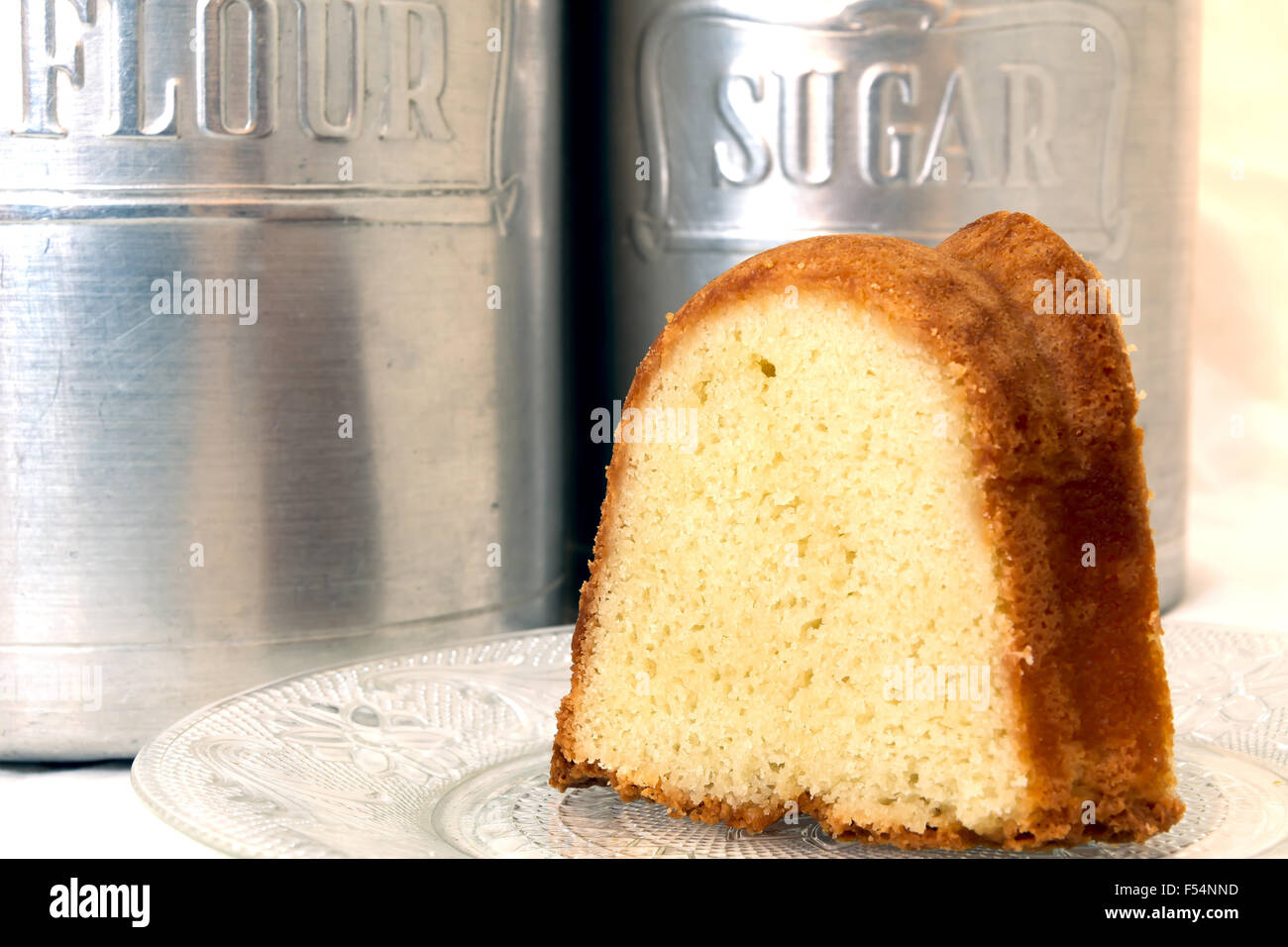 Fetta di ciambellone closeup con la farina e lo zucchero e i barattoli in background. Foto Stock